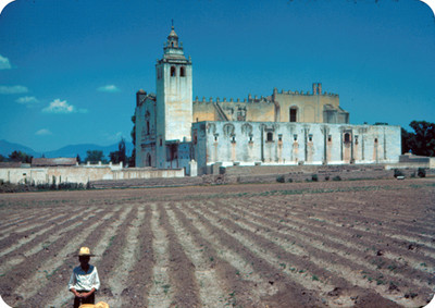Campesino en un campo, al fondo el convento de San Miguel Arcangel