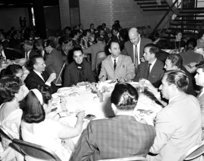 Hombres y mujeres platican en una mesa durante banquete en un salón
