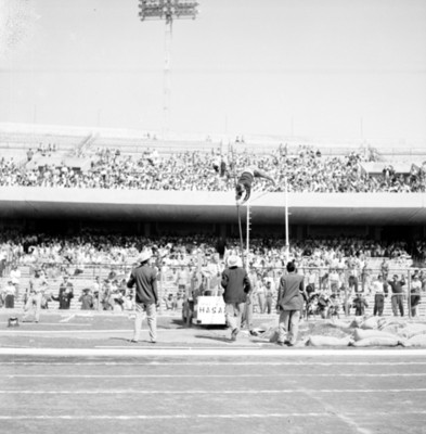 Gente observa a un atleta durante salto de garrocha