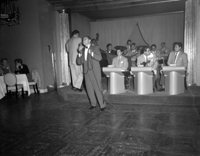 Cantante interpreta número musical durante reunión en restaurante versalles