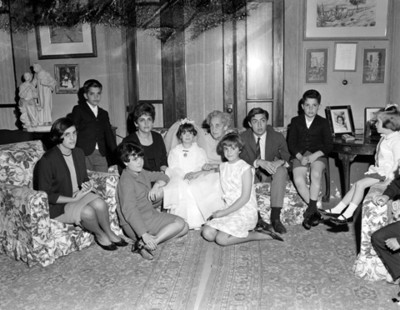 Familia reunida en sala durante festejo de primera comunión, retrato de grupo