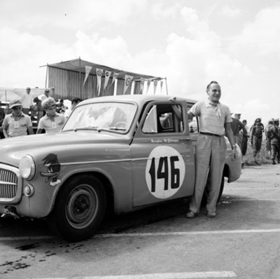 Hombre junto a automóvil de carreras en autódromo, retrato