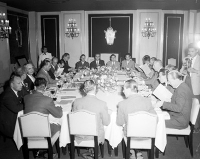 Hombres revisan documentos durante banquete en un salón
