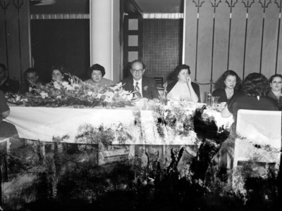 Hombres y mujeres en comedor de un salón durante banquete