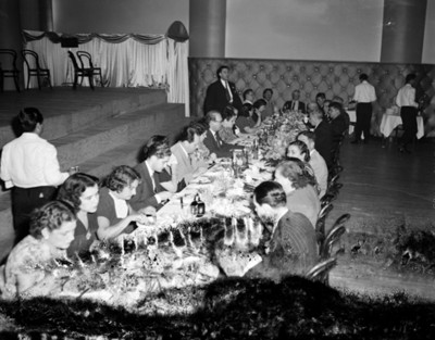Hombres y mujeres durante banquete en un salón