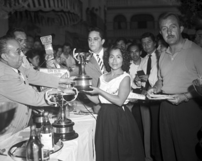 Hombre y mujer sostienen trofeos de la carrera de meseros Bacardí
