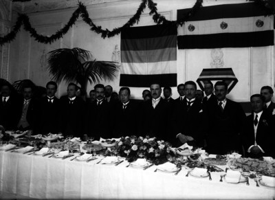 Aarón Sáenz acompañado de otras personas durante un banquete, retrato de grupo
