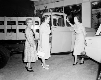 Mujeres junto a transporte de carga en una agencia automotríz