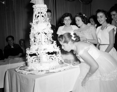 Quinceañera sopla velas de un pastel durante fiesta
