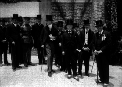 Georges T. Summerling dialogando con varios hombres al parecer durante un evento social, retrato de grupo