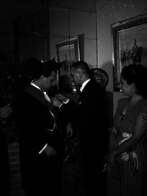 Jaime Torres Bodet es condecorado por un hombre, durante una ceremonia en un salón