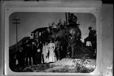 Hombres y mujeres junto a la locomotora de un tren, retrato