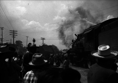 Gente y ferrocarrileros observando el choque de un ferrocarril y una locomotora