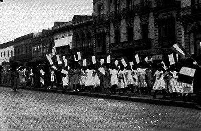 Niñas con banderas caminan por una calle