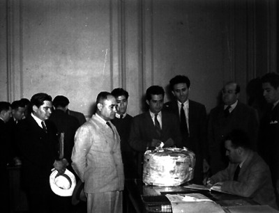 Funcionarios observando a otro firmar un documento