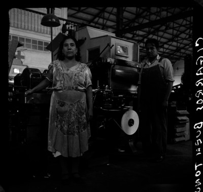 Trabajadores frente a una máquina de la fábrica de cigarros "El Buen Tono", retrato