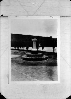 Mujer camina frente a la fuente de un jardín