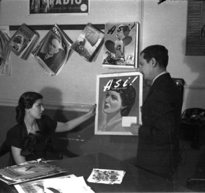 Gloria Marín observando un album fotográfico, en el interior de una empresa periodística